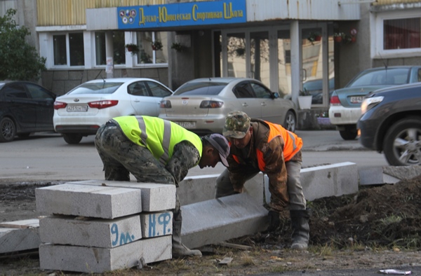 Рабочие устанавливают новые бордюрные камни  из гранита на ул. Брусницына