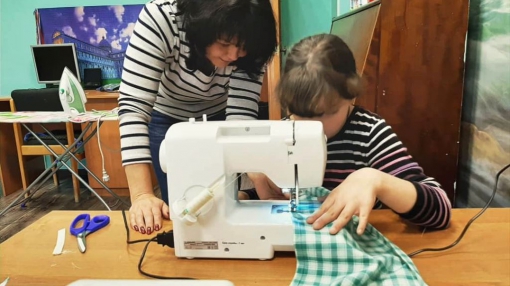 Татьяна Сняткова учит девочку из социально-реабилитационного центра для несовершеннолетних обращаться со швейной машинкой