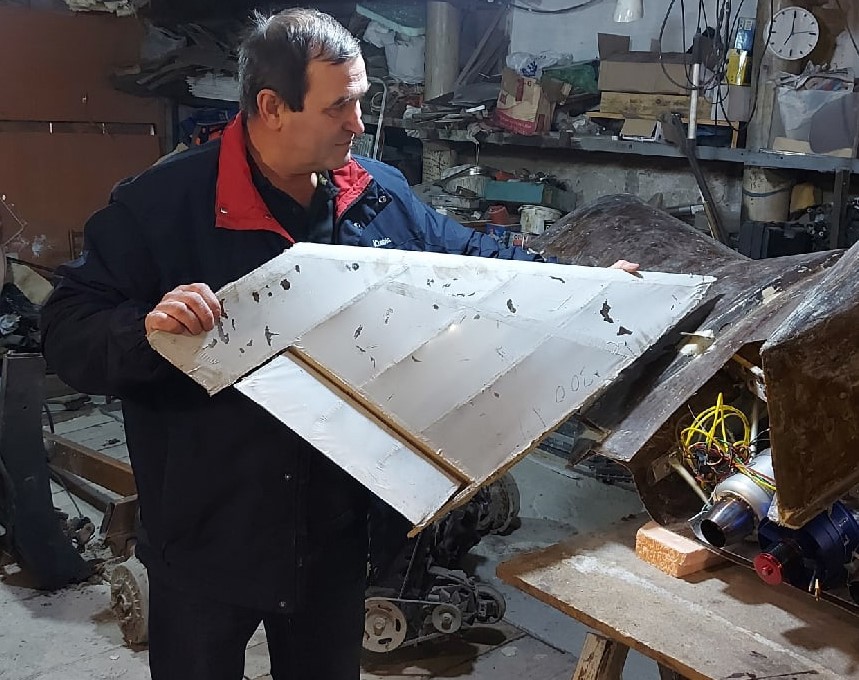 Кирилл Аваев прикладывает к модели самолета киль, которому еще предстоит стать частью устройства