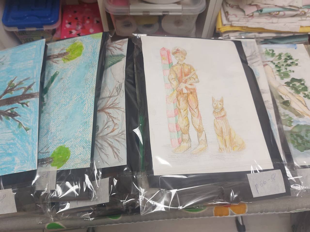 Мария Варламова вкладывает рисунки в пакеты с одеждой для военнослужащих