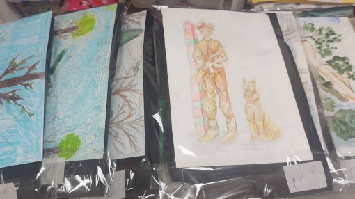 Мария Варламова вкладывает рисунки в пакеты с одеждой для военнослужащих