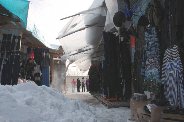 Не дожидаясь, пока снег завалит покупателей, продавцы рынка помогают ему скорее упасть. Фото Ольги Брынцевой